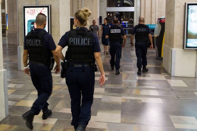 Passengers and police officers walk in the train station of Nimes after it was reopen on August 19, 2017