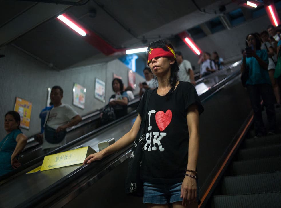 Hong Kong pro-democracy activist covers her eyes with the Chinese flag