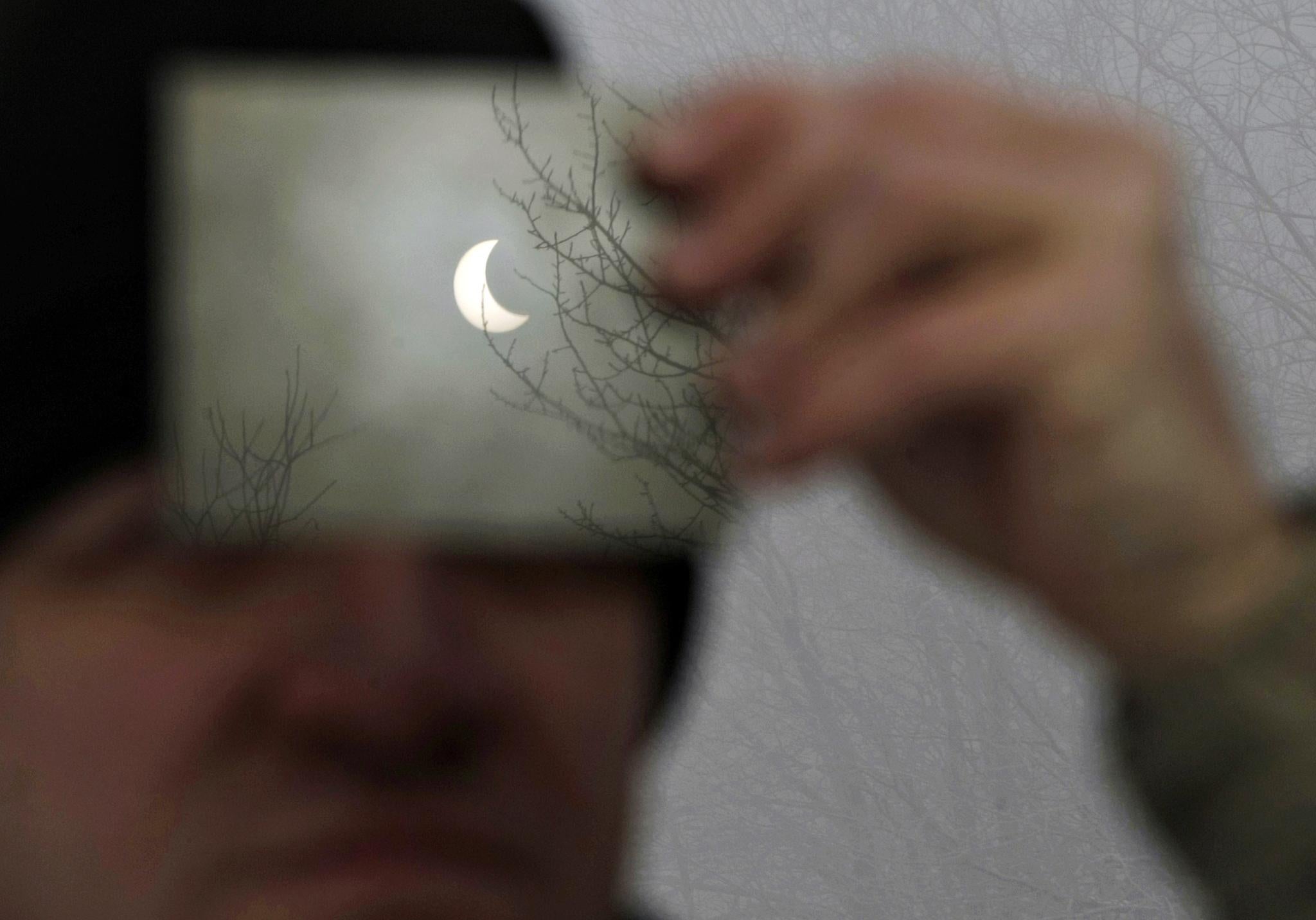 A man watches a partial solar eclipse through a filter in Galyateto, some 100 km (62 miles) east of Budapest, January 4, 2011