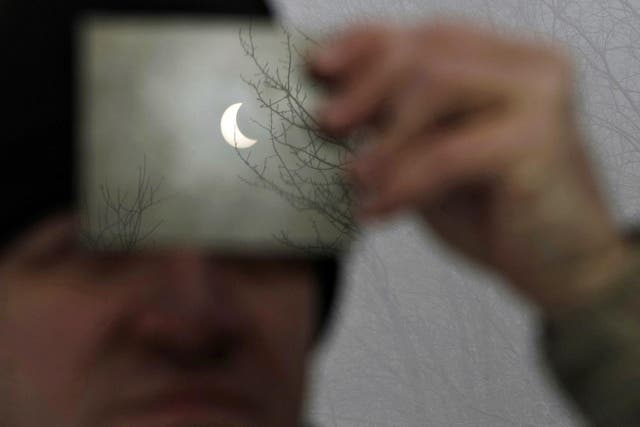 A man watches a partial solar eclipse through a filter in Galyateto, some 100 km (62 miles) east of Budapest, January 4, 2011