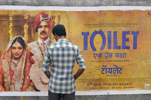 An Indian man inspects a poster for the Hindi film 'Toilet' in Hyderabad