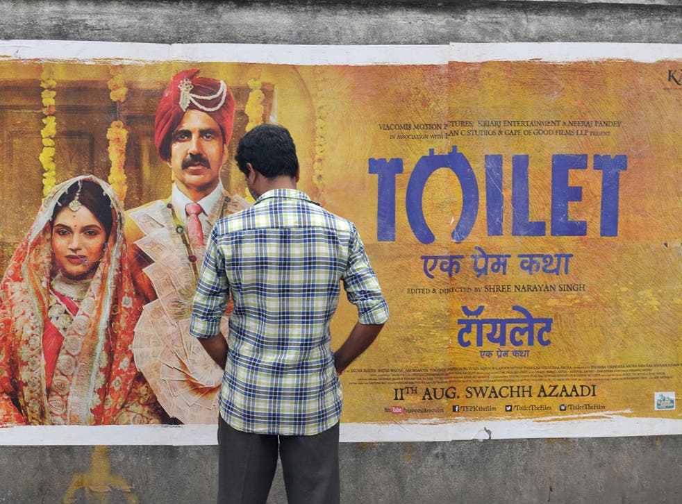 An Indian man inspects a poster for the Hindi film 'Toilet' in Hyderabad