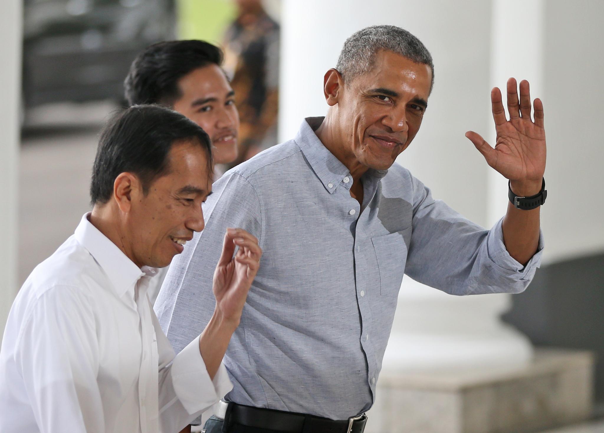 Former US president Barack Obama waves at reporters as he walks with Indonesian President Joko Widodo