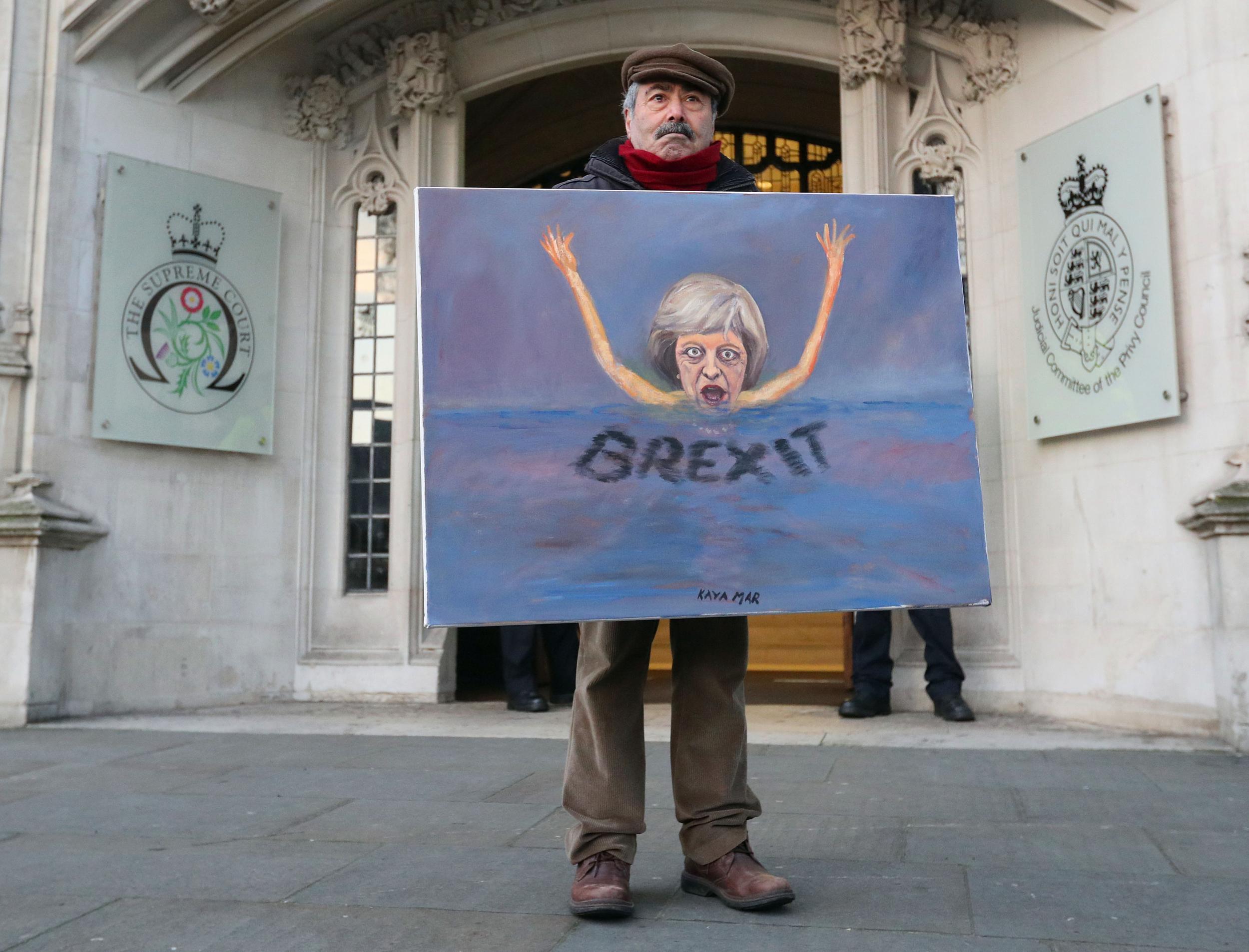 Satirical artist Kaya Mar poses with a Brexit-themed artwork depicting British Prime Minister Theresa May, as he stands outside the Supreme Court in London in January