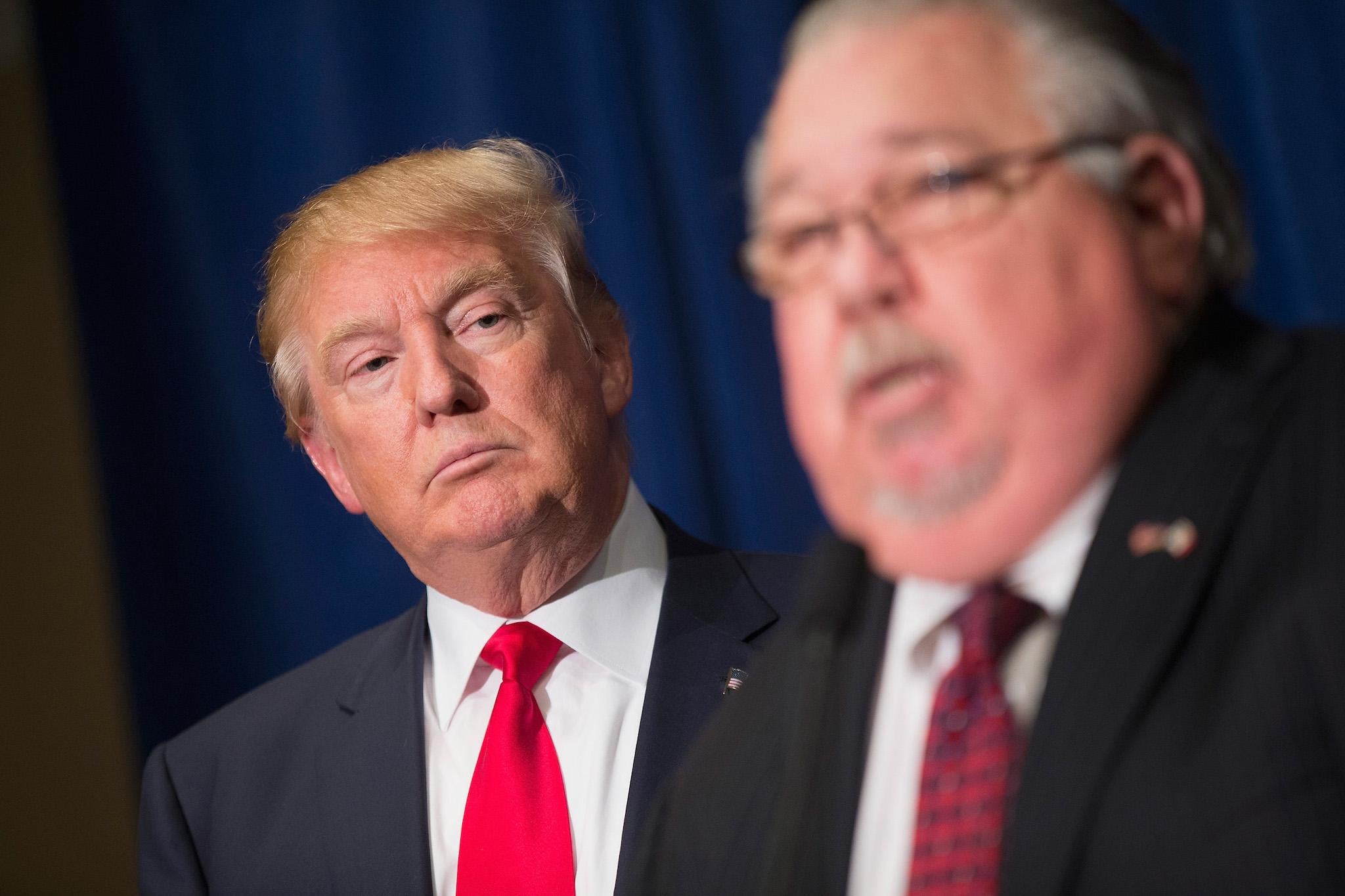 Republican presidential candidate Donald Trump listens as Sam Clovis speaks at a press conference
