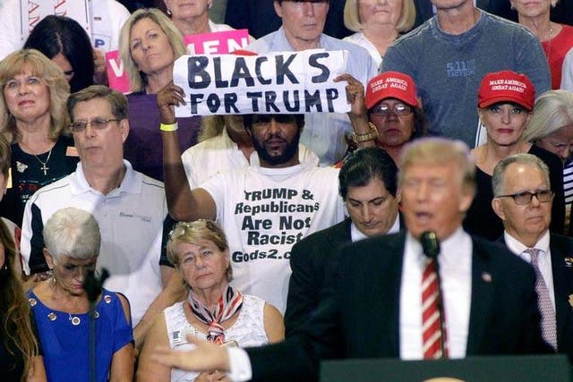 Maurice Symonette holds up his much noted sign behind President Trump at a rally in Arizona on Tuesday