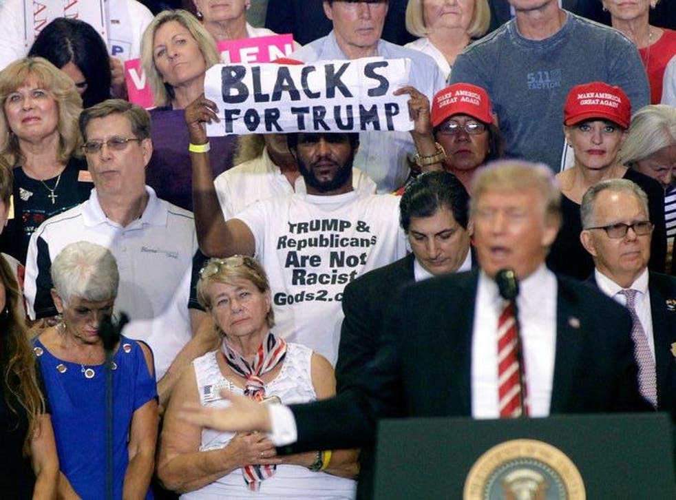 Maurice Symonette holds up his much noted sign behind President Trump at a rally in Arizona on Tuesday