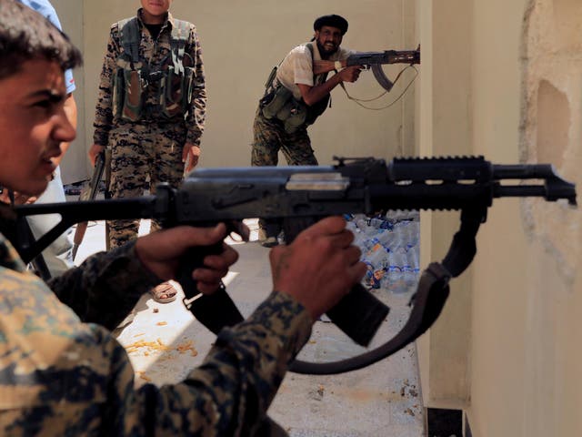  Members of the Syrian Democratic Forces try to locate an Isis sniper in Al Senaa, a district of Raqqa earlier this month