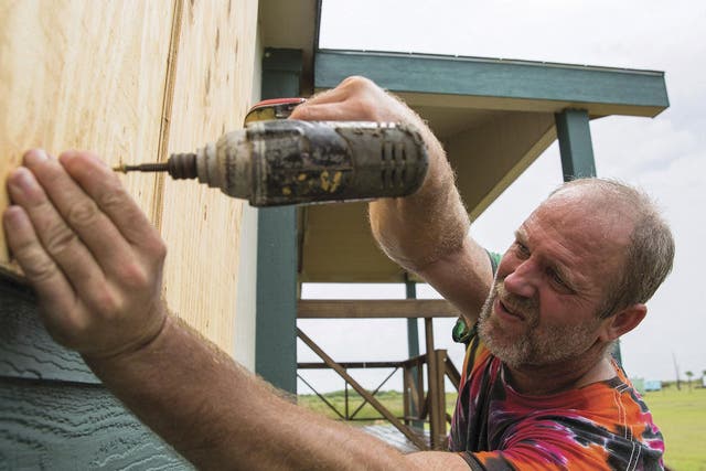 Jim Gilbert, owner of the Saltwater Saloon and J&T One Stop, boards up a window at his home in Magnolia, Texas