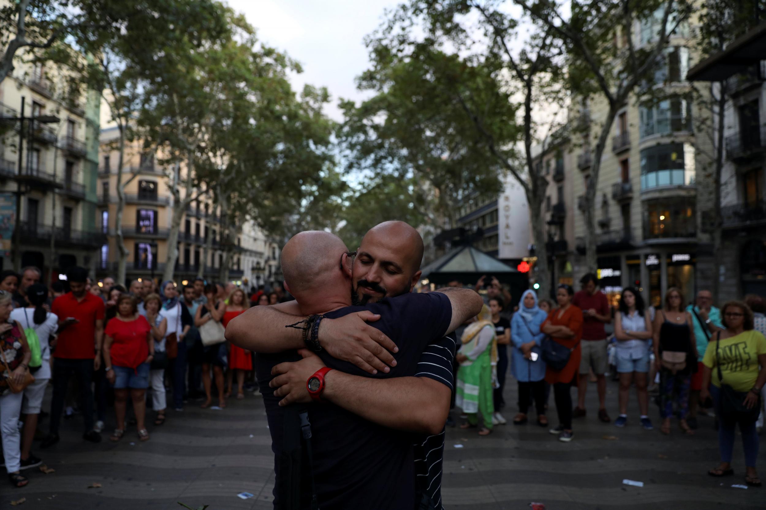 A Muslim man gives hugs next to a sign reading: "I am Muslim, I am not a terrorist. I share hugs of love and peace"