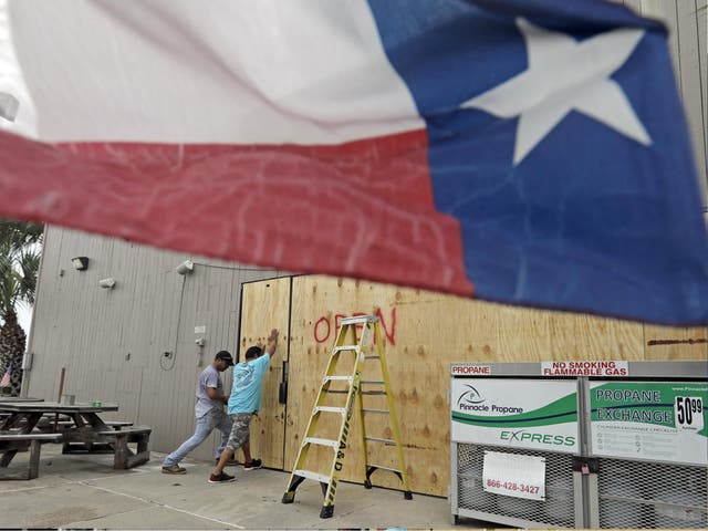 Ramon Lopez, left, and Arturo Villarreal board up windows of a business in Galveston, Texas as Hurricane Harvey intensifies in the Gulf of Mexico 