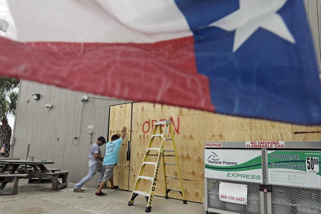 Ramon Lopez, left, and Arturo Villarreal board up windows of a business in Galveston, Texas as Hurricane Harvey intensifies in the Gulf of Mexico 