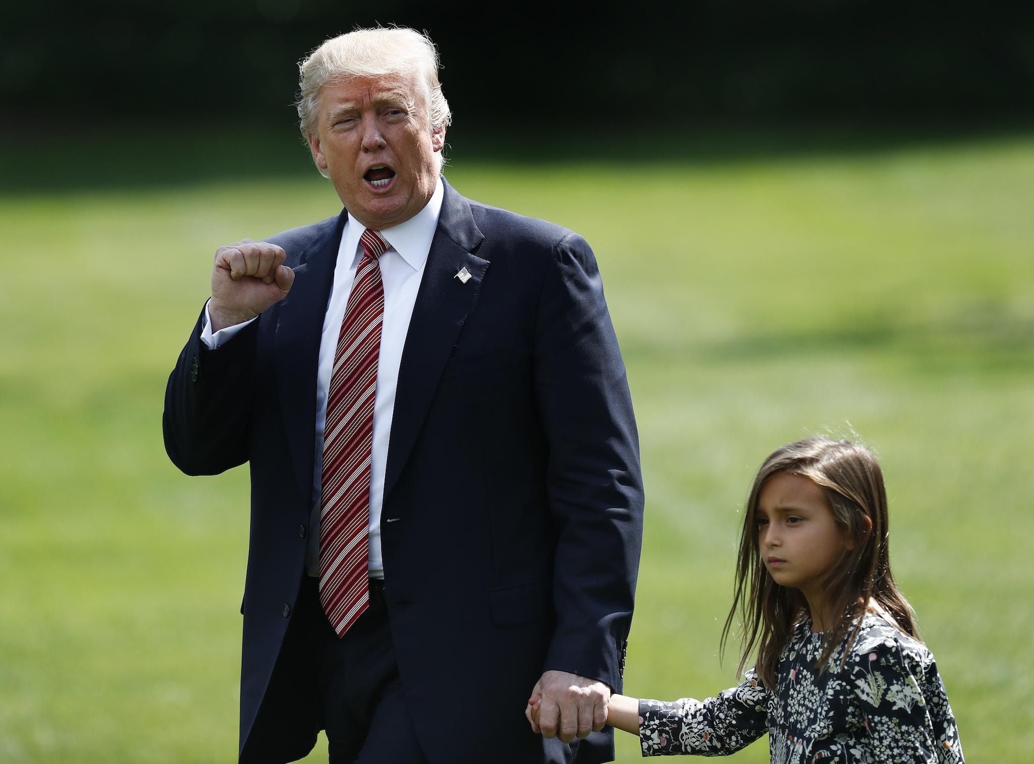 President Donald Trump gestures to the media as he walks with his granddaughter Arabella Kushner
