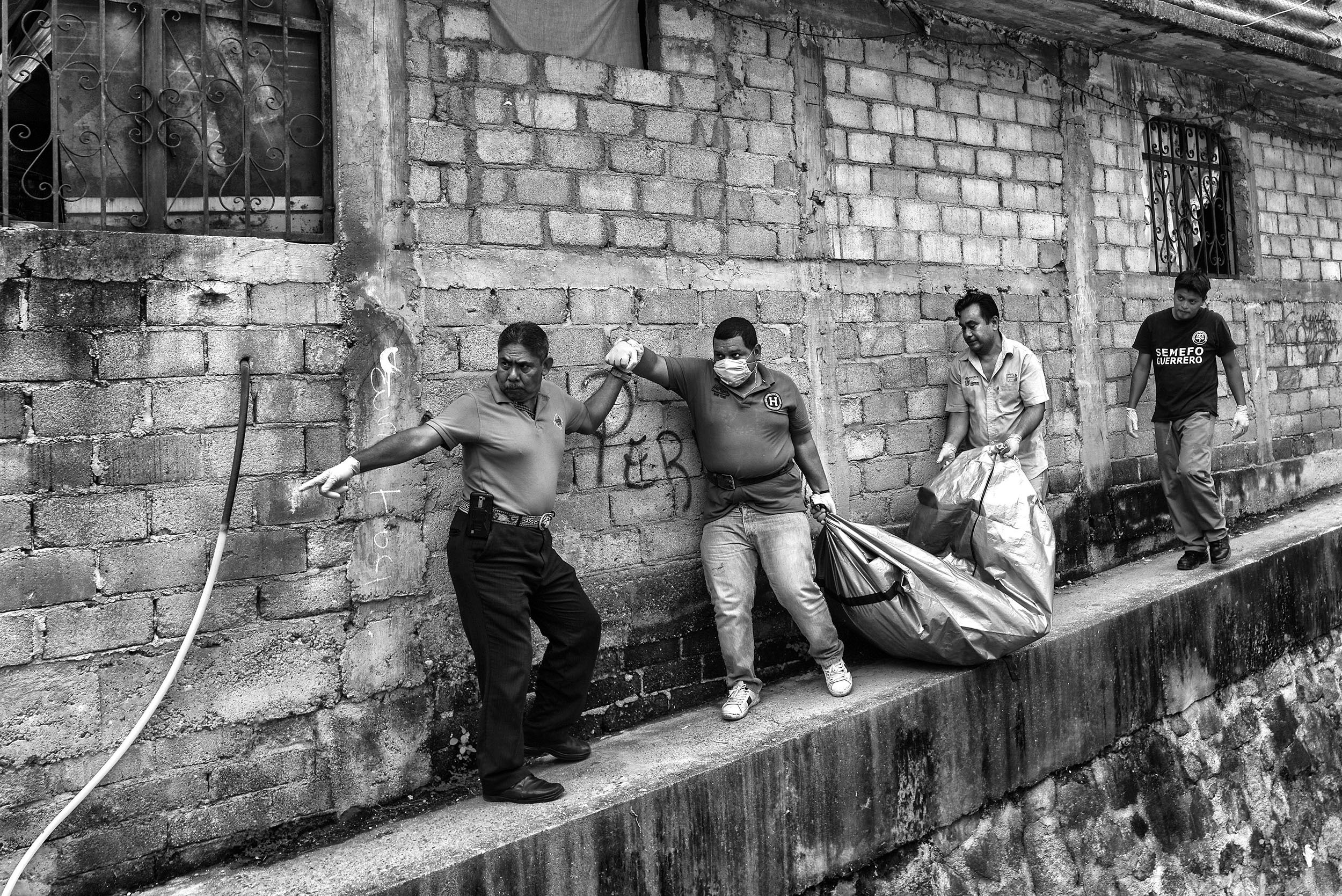 Coroners remove a body from Colonia Barranca de la Laja, an impoverished neighbourhood in Acapulco. The decapitated and dismembered corpse was buried beneath a floor