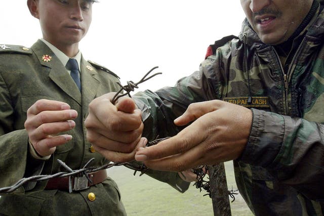 A Chinese soldier and an Indian soldier constructing a barbed wire