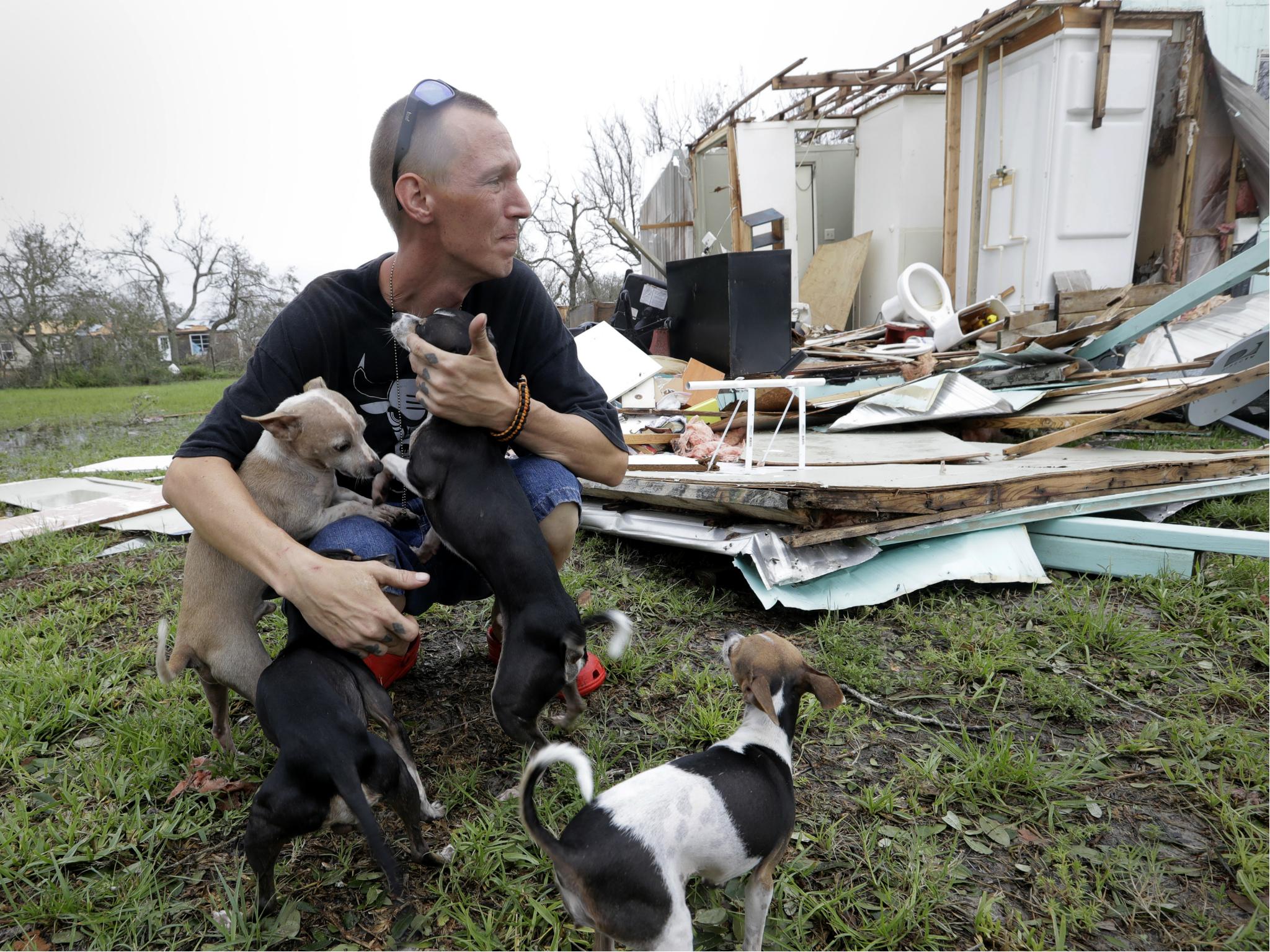 Sam Speights tries to hold back tears while holding his dogs and surveying the damage to his home in the wake of Hurricane Harvey 27 August in Rockport, Texas.