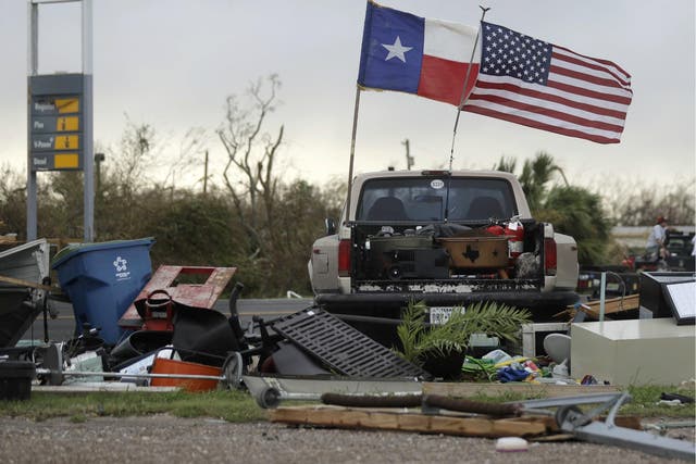 The Texas state flag and American flag wave in the wind over an area of debris left behind in the wake of Hurricane Harvey