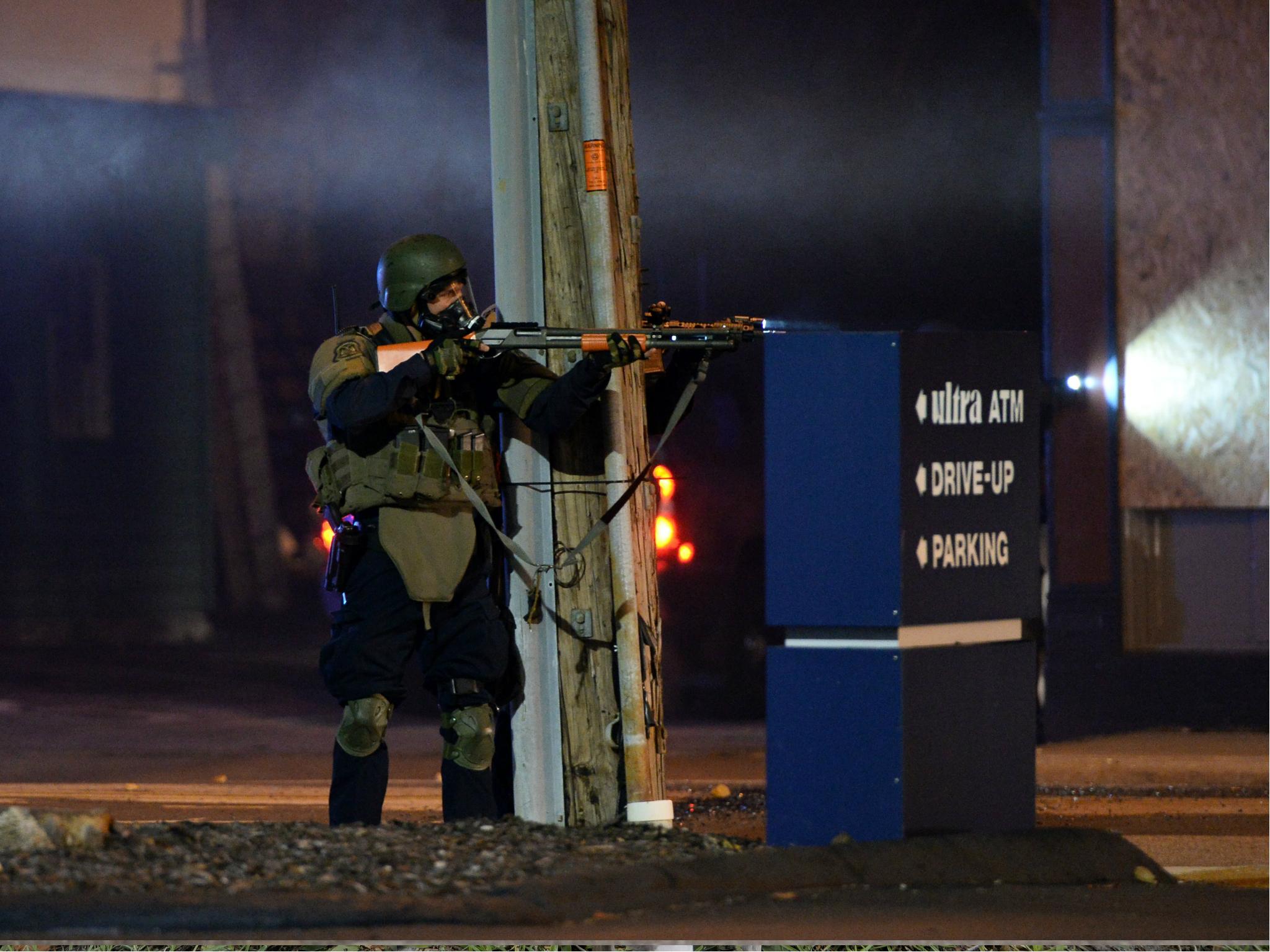 A state trooper aims his gun at protesters in Ferguson, Missouri, on 25 November 25 2014 during a demonstration one day after violent protests and looting following the grand jury decision in the Michael Brown police shooting case