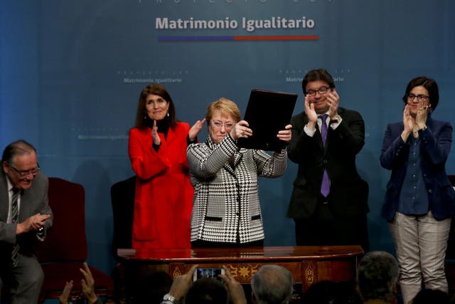 Chile's President Michelle Bachelet holds up a portfolio containing her signed proposal for a same-sex marriage bill at La Moneda presidential palace in Santiago