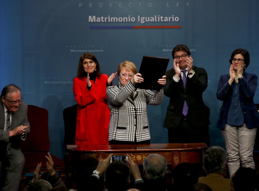 Chile's President Michelle Bachelet holds up a portfolio containing her signed proposal for a same-sex marriage bill at La Moneda presidential palace in Santiago