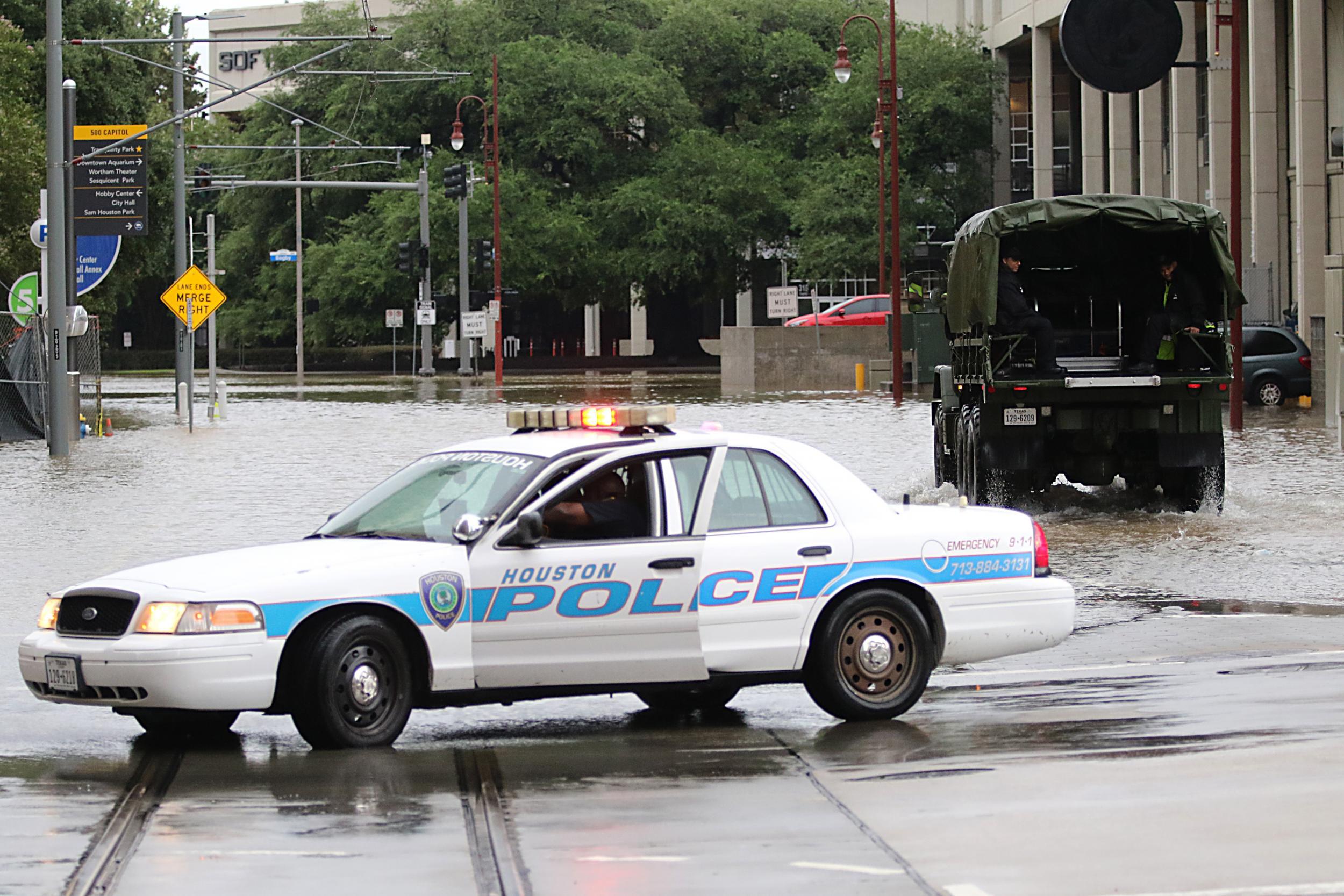 A Houston police officer blocks a flooded street as emergency services look for people stranded in flooded downtown Houston