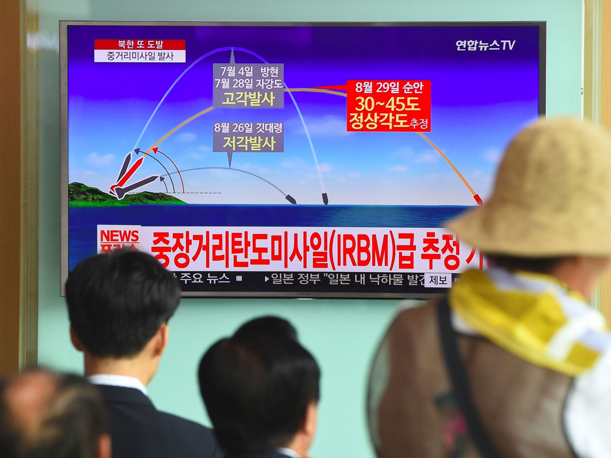 People watch a television news screen showing a graphic of a North Korean missile launch at a station in Seoul