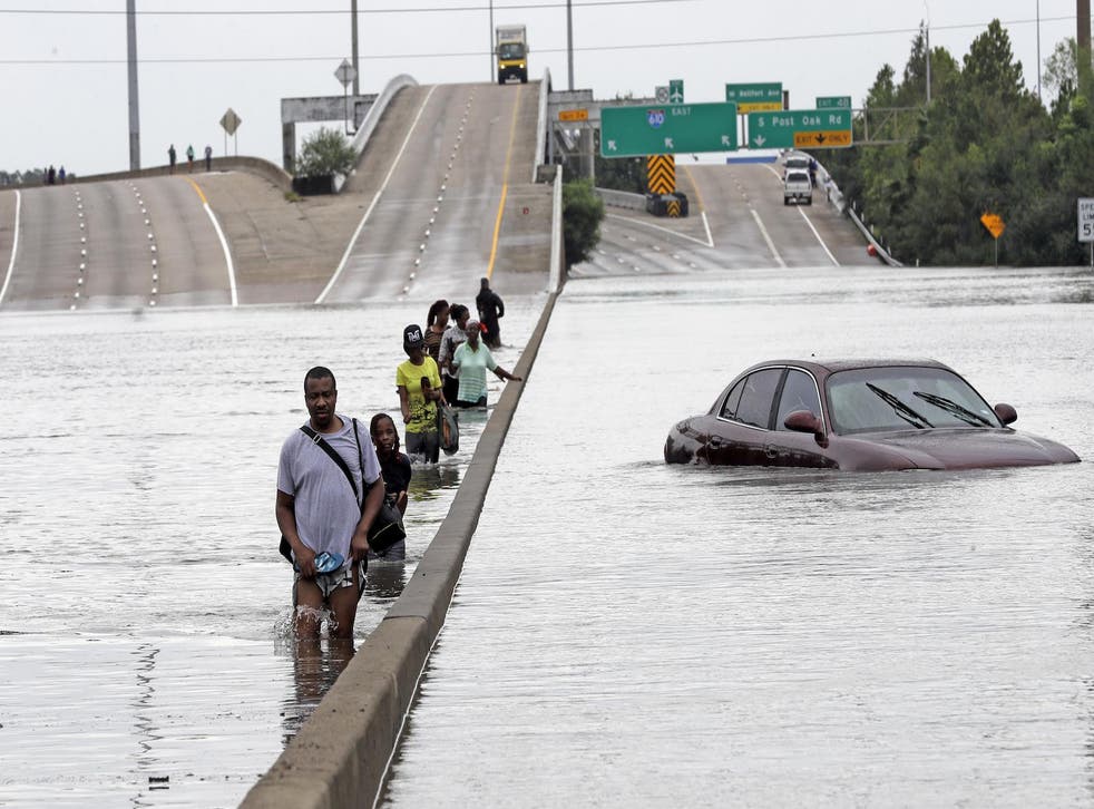 Evacuees wade down a flooded section of Interstate 610 as floodwaters from Tropical Storm Harvey rise Sunday, Aug. 27, 2017, in Houston