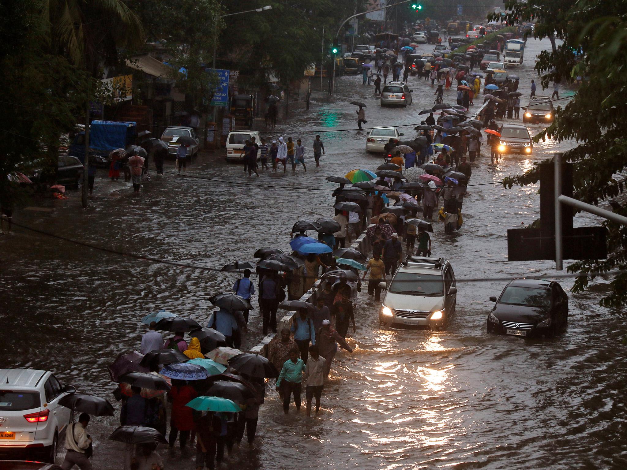 Commuters walk through water-logged roads after rains in Mumbai, India