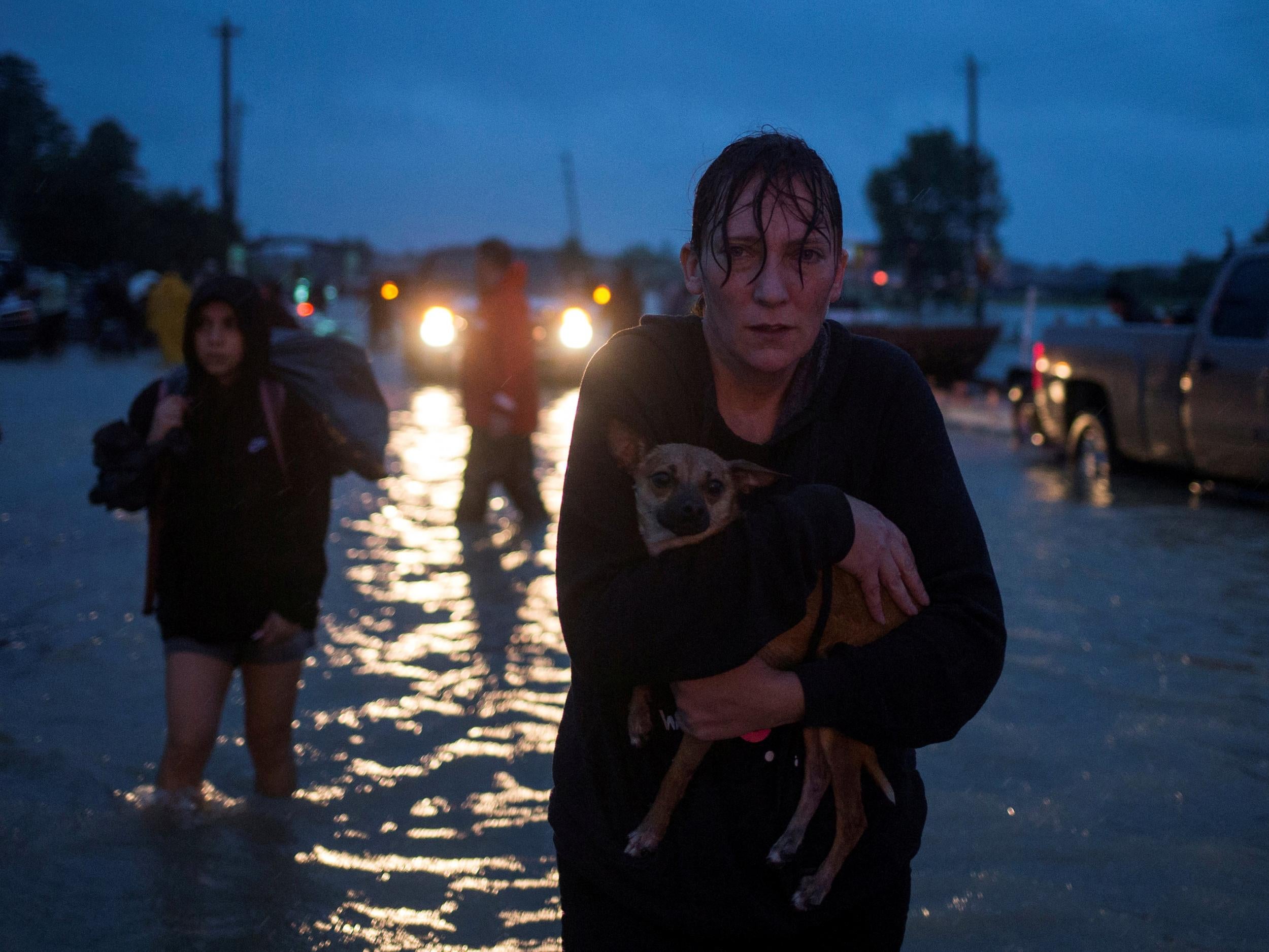 A woman holds her dog as she arrives to high ground after evacuating her home due to floods caused by Tropical Storm Harvey along Tidwell Road in east Houston, Texas