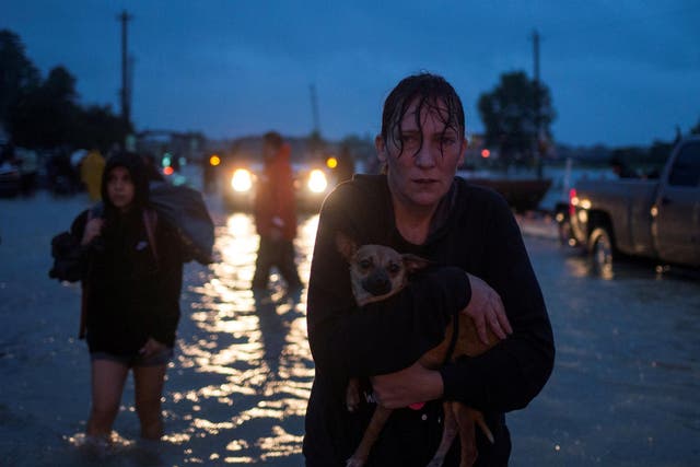 A woman holds her dog as she arrives to high ground after evacuating her home due to floods caused by Tropical Storm Harvey along Tidwell Road in east Houston, Texas