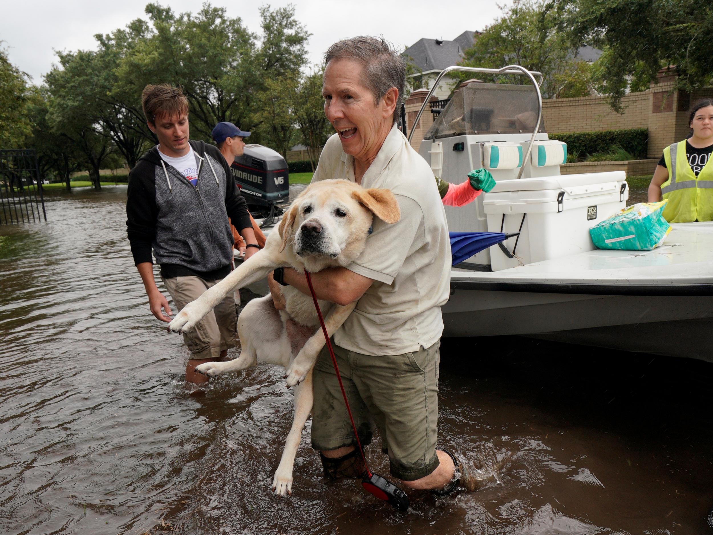 A man is evacuated by boat with his dog from the Hurricane Harvey floodwaters in Houston, Texas
