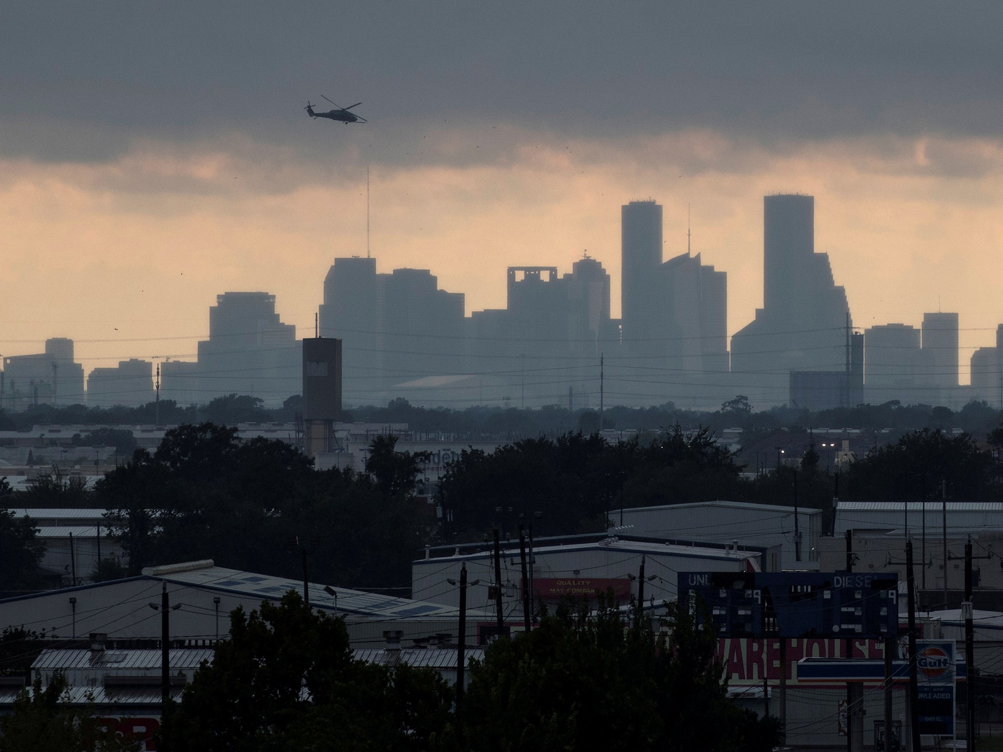 A helicopter hovers above the Houston skyline as sunlight breaks through storm clouds from Tropical Storm Harvey in Texas