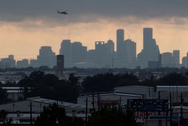 A helicopter hovers above the Houston skyline as sunlight breaks through storm clouds from Tropical Storm Harvey in Texas
