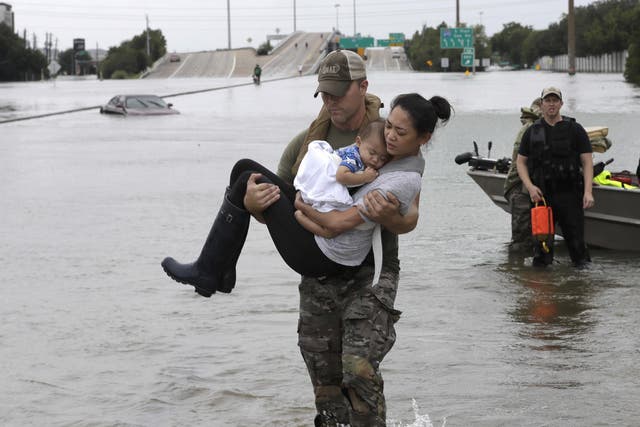Police SWAT officer Daryl Hudeck carries Catherine Pham and her 13-month-old son Aiden after rescuing them from their home surrounded by floodwaters from Tropical Storm Harvey