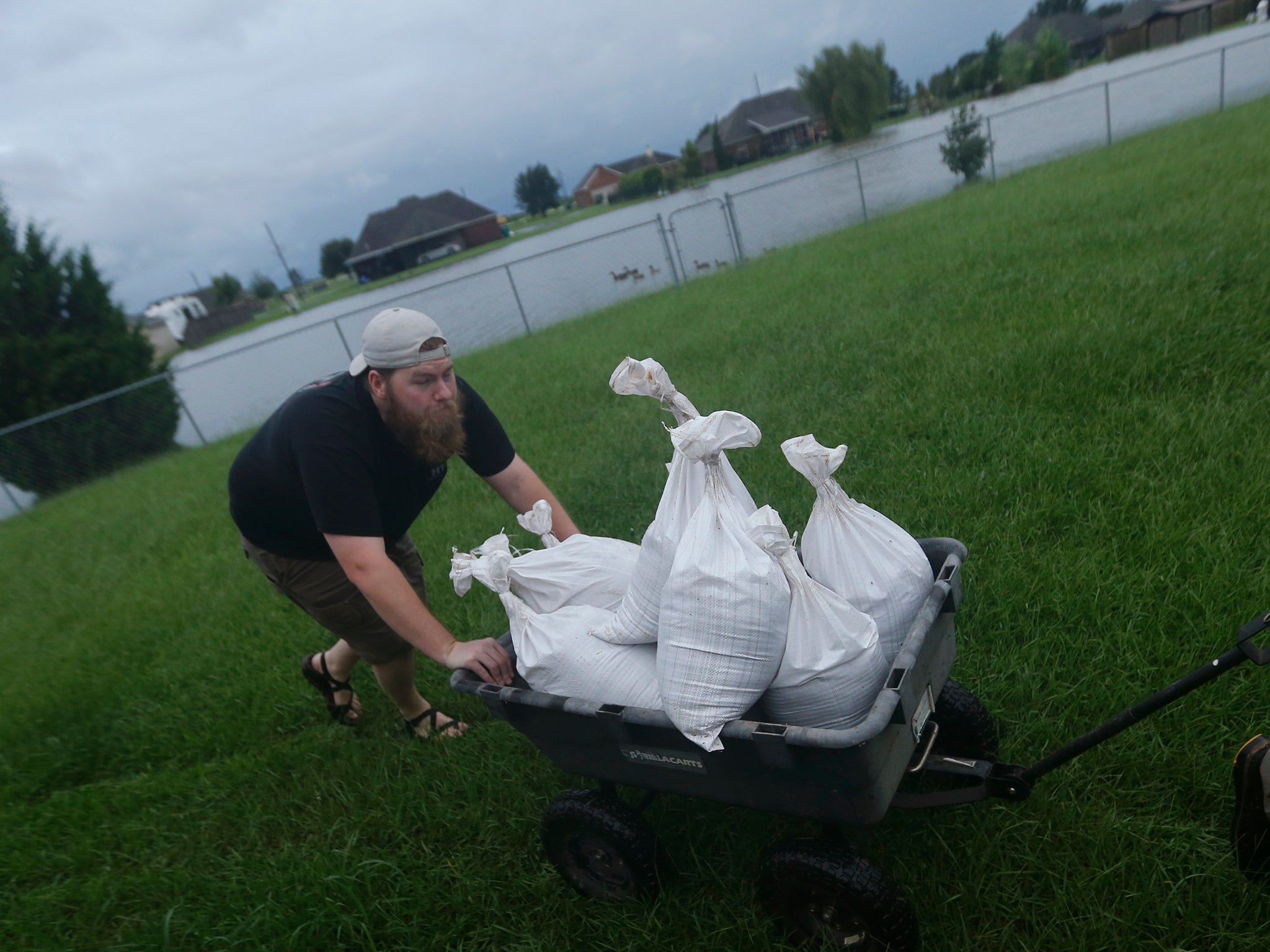 Cody McLemore pushes a wagon filled with sandbags as he fortifies his house in the flooded Clearfield Farm subdivision, in anticipation of more flooding from Tropical Storm Harvey, in Lake Charles, Louisiana