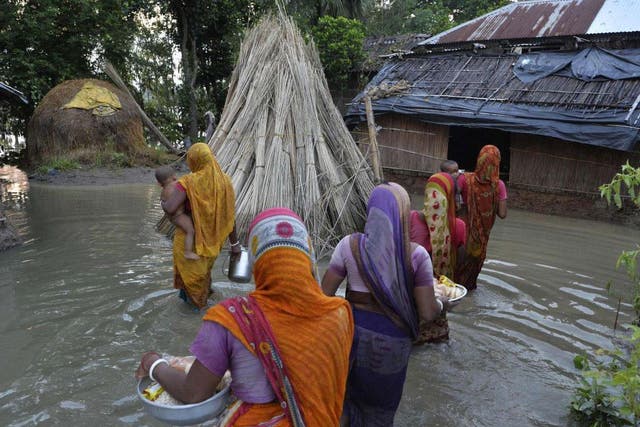 Cillagers wade through flood waters after collecting relief food near the submerged houses in Gazole village at Malda district in the Indian state of West Bengal