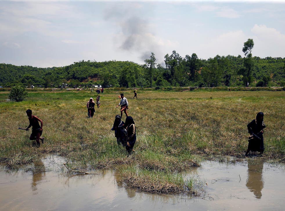  Rohingya people try to come to the Bangladesh side from No Man's Land as smoke rises after a gunshot was heard on the Myanmar side, in Cox's Bazar, Bangladesh