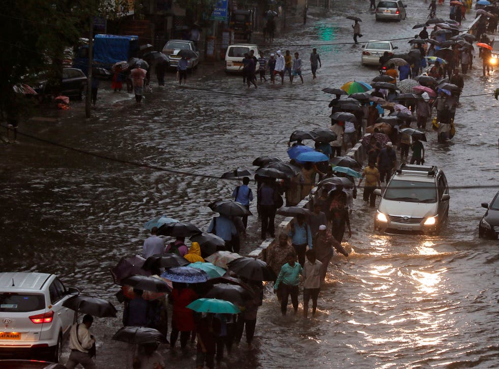 Commuters walk through waterlogged roads after torrential rains in Mumbai, India