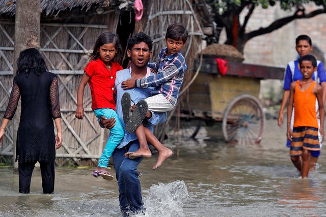 A man wades toward a rescue boat through a flooded village in the eastern state of Bihar, India