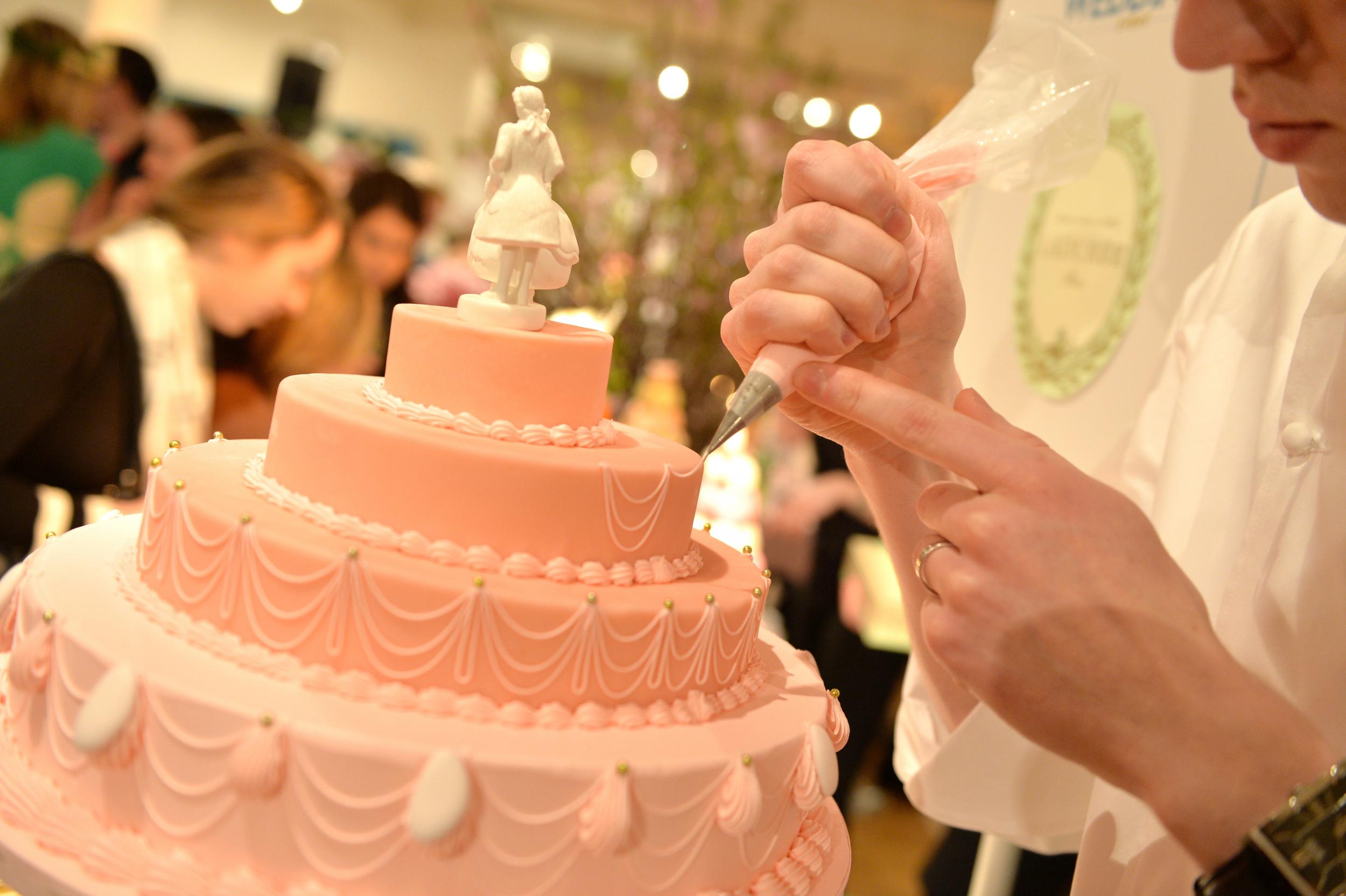A stock photo of a wedding cake is pictured being worked on