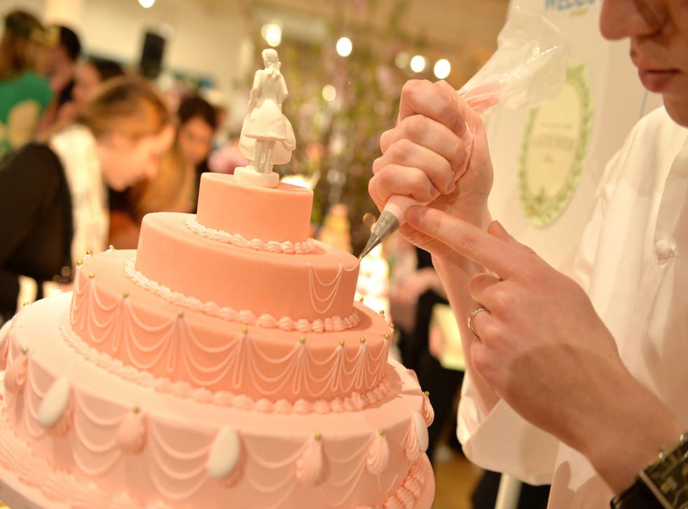 A stock photo of a wedding cake is pictured being worked on