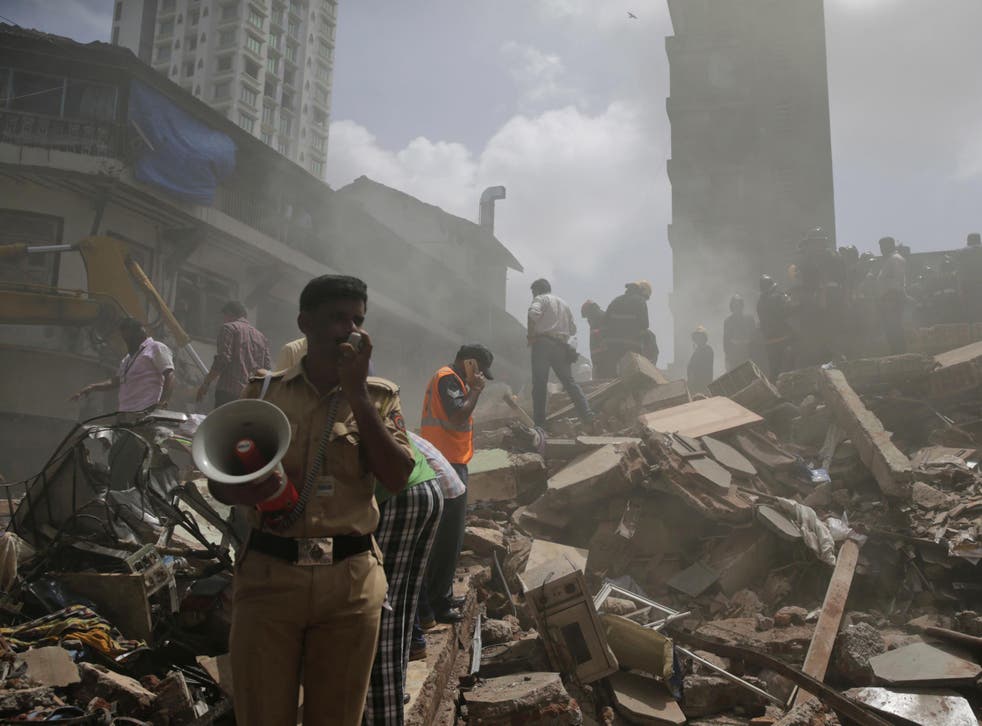A policeman makes an announcement on a loudspeaker at the site of the building collapse in Mumbai, India