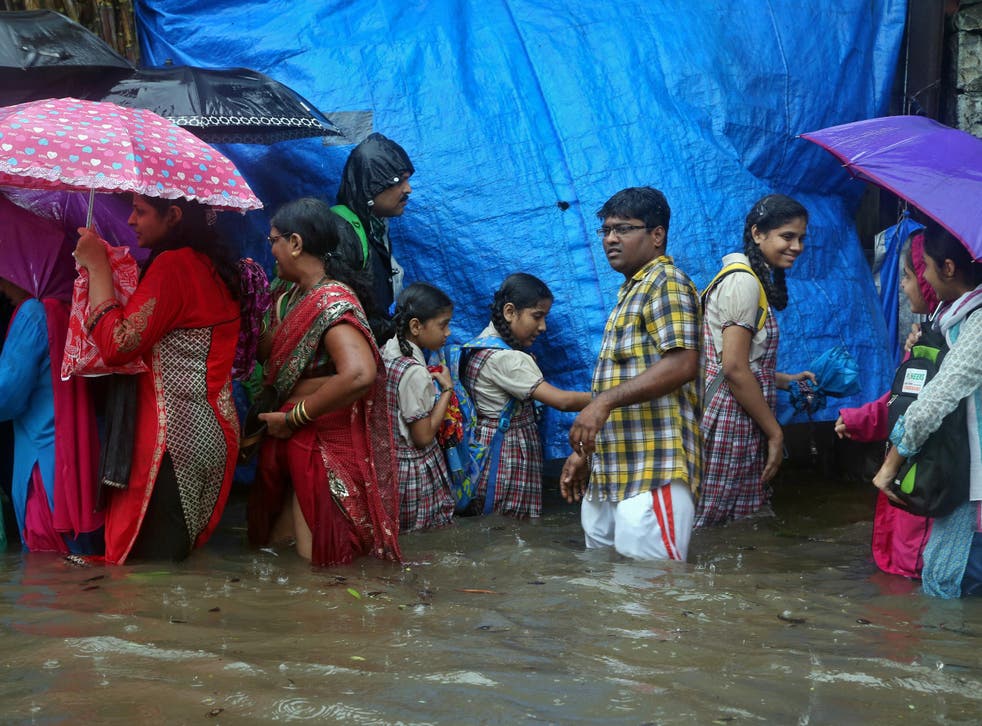 People wade through a water-logged road in Mumbai, India, as late August rains devastate southern Asia