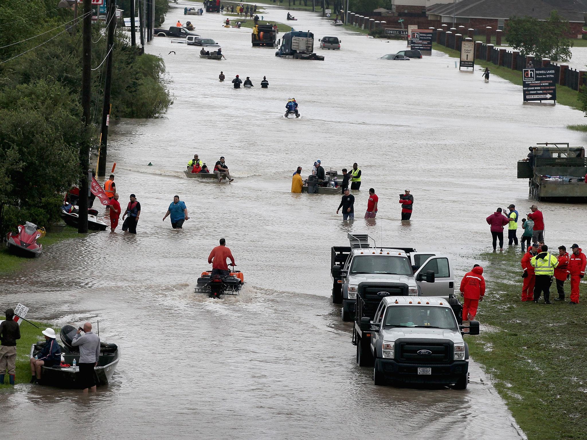 People make their way out of a flooded neighborhood after it was inundated with rain water following Hurricane Harvey