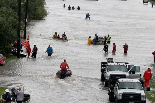 People make their way out of a flooded neighborhood after it was inundated with rain water following Hurricane Harvey