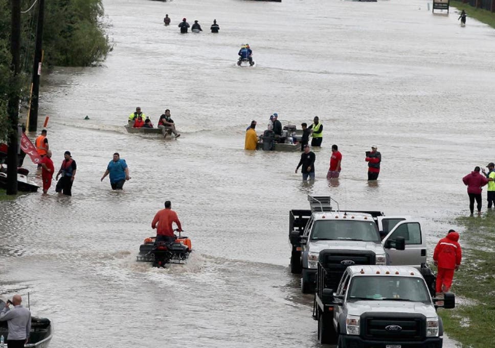 People make their way out of a flooded neighborhood after it was inundated with rain water following Hurricane Harvey