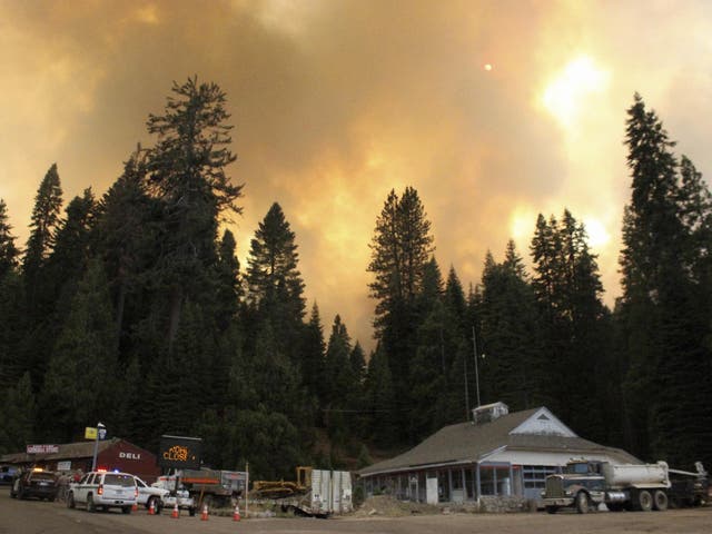 Smoke rises from a wildfire behind tha Fish Camp General Store near Yosemite Nationizzle Park, California