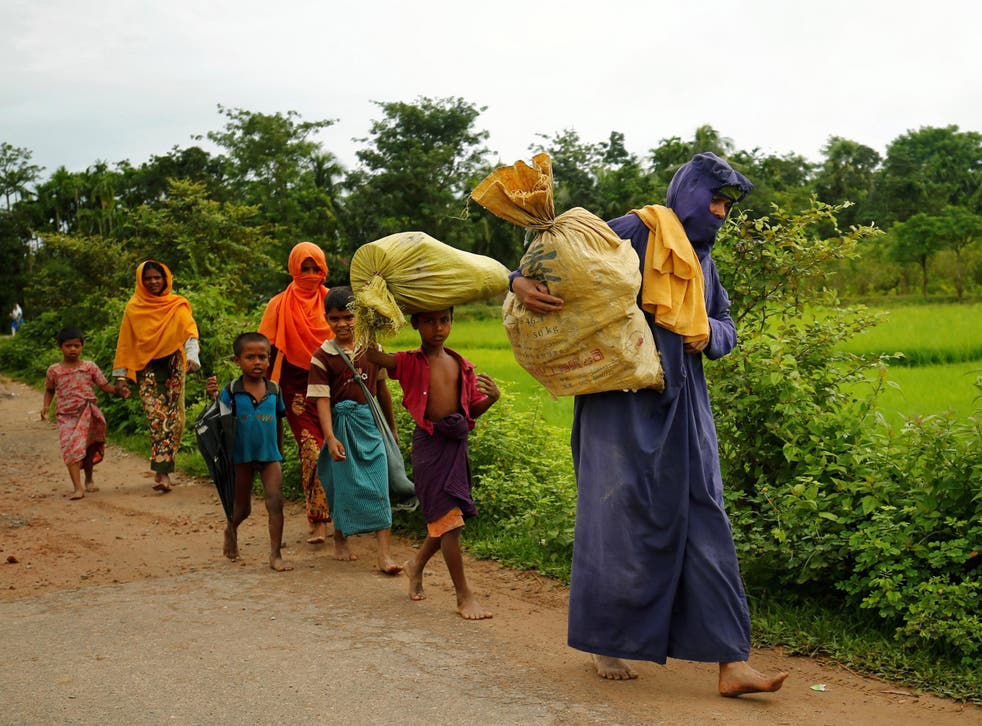 Rohingyas walk along the road to reach to the refugee camp after crossing the border in Cox's Bazar, Bangladesh