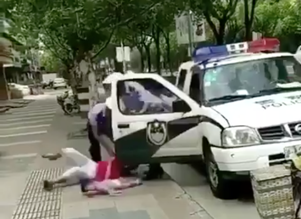 Video shows a policeman throw a woman and child to the ground amid a row over a parking ticket