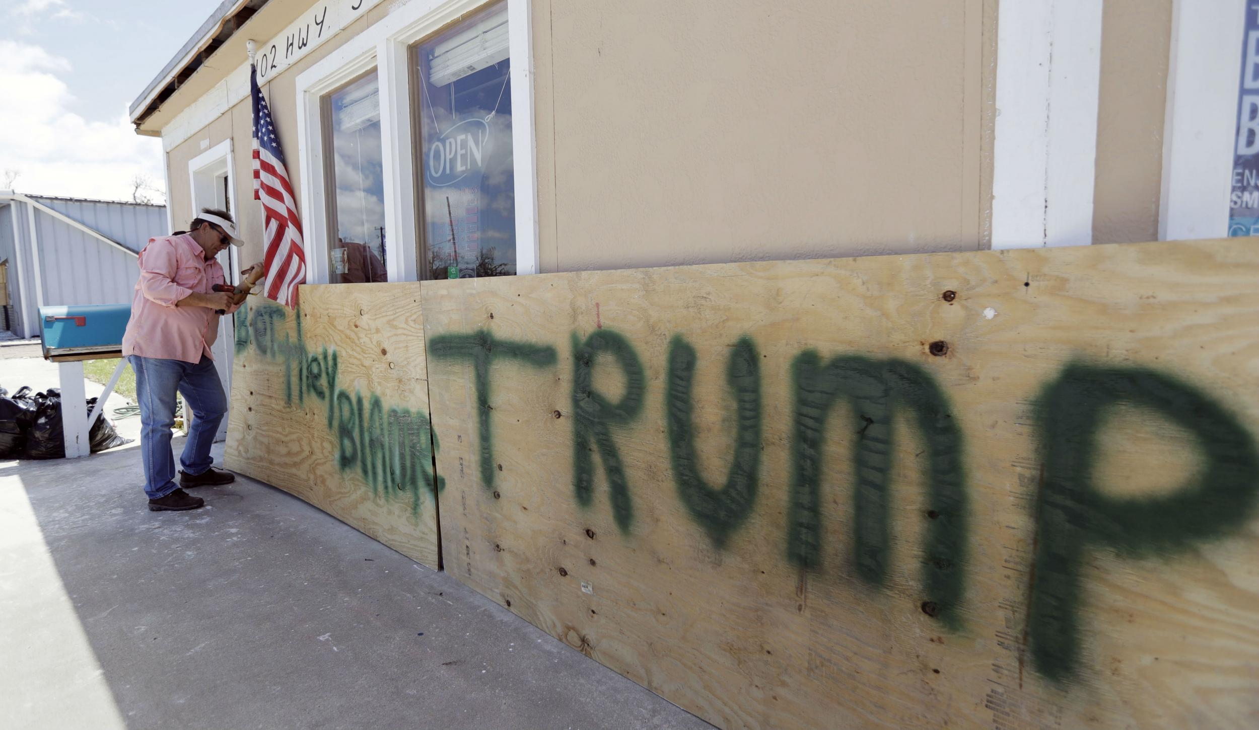 A Houston man attaches a sign reading ‘Bet They Blame Trump’ at his business damaged in the wake of Harvey